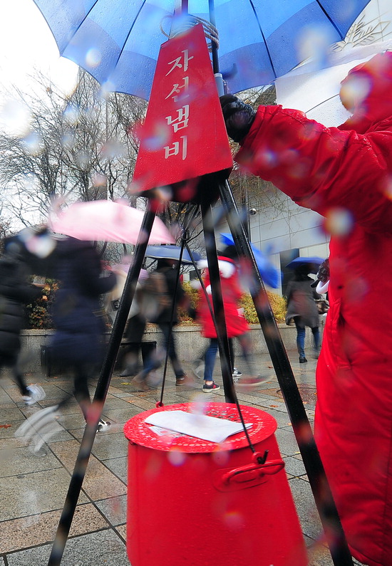 ▲ 전국적으로 겨울비가 내린 22일 인천시 남구 관교동 거리에서 우산을 쓴 시민들이 구세군 사전냄비 앞을 지나고 있다.  최민규 기자 cmg@kihoilbo.co.kr