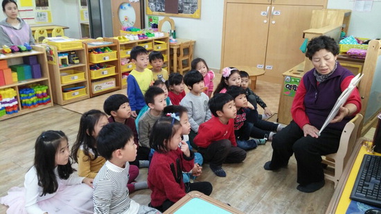 ▲ 어린이집을 방문한 노인이 아이들에게 그림책을 읽어주고 있다.