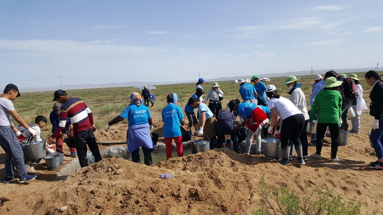 ▲ 인천지역 자원봉사자들이 몽골 현지 주민들과 함께 관수작업을 하고 있다.  김희연 기자