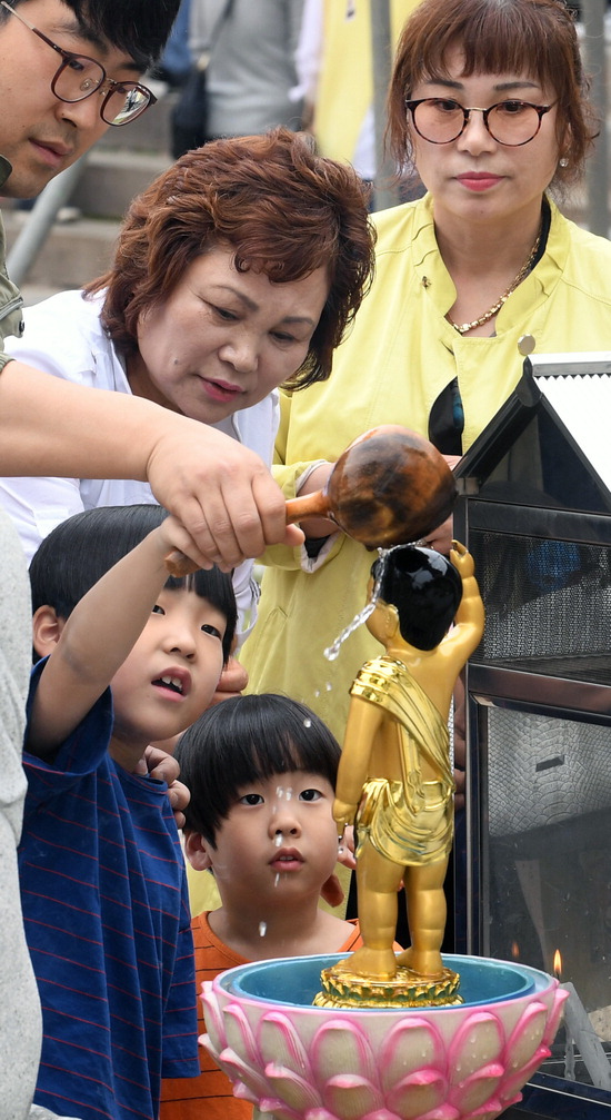 ▲ 부처님 오신 날인 22일 인천시 남구 수도사를 찾은 가족 단위의 시민들이 아기부처를 씻겨주는 관불의식을 하고 있다.  이진우 기자 ljw@kihoilbo.co.kr