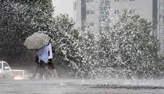 ▲ 장마전선의 영향으로 중부지방 대부분 지역에 많은 양의 비가 내린 26일 인천시 남동구 구월동의 한 거리에서 우산을 쓴 시민들이 차량이 일으킨 물보라 사이로 발길을 재촉하고 있다.  이진우 기자 ljw@kihoilbo.co.kr