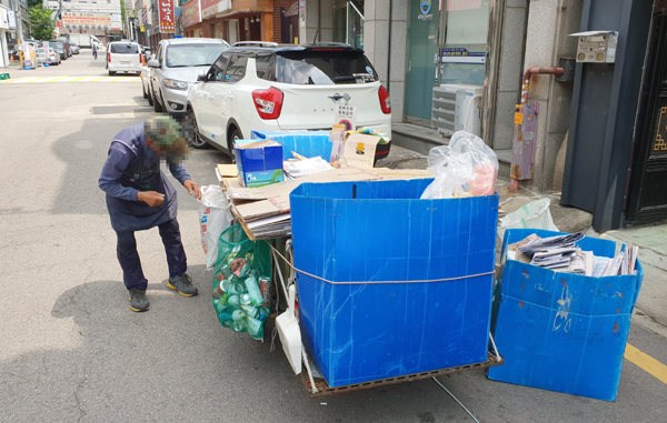 ▲ 31일 수원시의 도로상에서 한 노인이 수거한 재활용품을 손수레에 담고 있다.  박종현 인턴기자