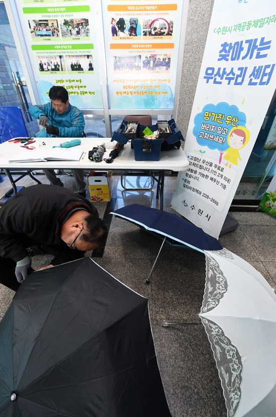 ▲ 수원시 지역공동체 일자리사업의 하나로 마련된 ‘찾아가는 우산 수리센터’가 31일 수원시 영통구 태장동 주민센터 로비에 마련돼 전문 교육을 받은 기술자들이 우산을 고쳐 주고 있다.홍승남 기자 nam1432@kihoilbo.co.kr