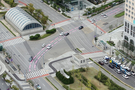 도로에 컬러유도선(분홍색)이 그려져 차량 흐름에 도움을 주고 있는 인천 송도국제도시 내 인천도시철도 1호선 센트럴파크역 주변 도로. <인천경제자유구역청 제공>