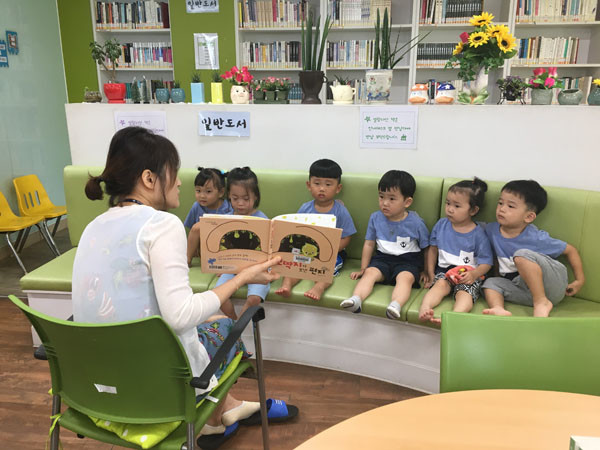 꿈나무 작은도서관에서 어린이들이 동화책 내용에 귀 기울이고 있다.