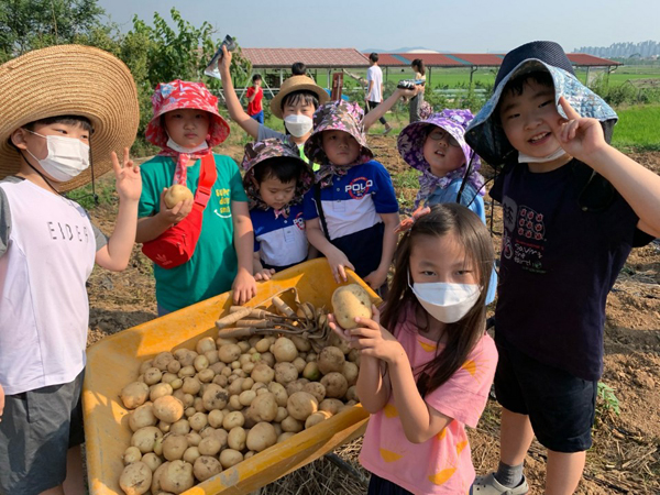 수확한 감자를 보고 환하게 웃고있는 학생들.