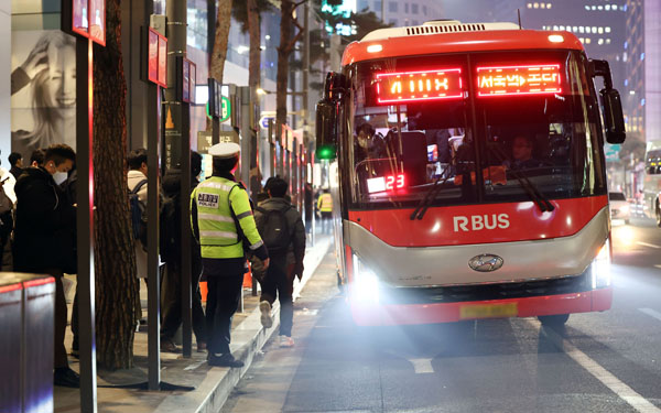 지난 5일 저녁 서울 중구 명동에서 퇴근길 시민들이 버스를 기다리고 있다.    서울시는 명동입구 광역버스 정류소에 노선 표시 안내판(줄서기 표지판)을 설치한 뒤 오히려 퇴근길 차량 정체가 심해지자 표지판 운영을 이달 31일까지 유예하기로 했다./연합뉴스