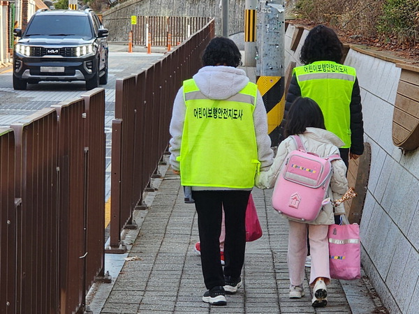수원시 한 초등학교 앞 어린이 보호구역에서 어린이 보행안전지도사가 어린이와 함께 등교한다.