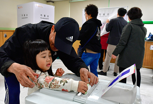 용현여중에 마련된 투표소에서 한 유권자가 딸과 함께 투표 용지를 넣고 있다.